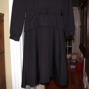 May include: A black long-sleeved dress with a cinched waist and a flowing skirt.