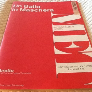 May include: A red booklet with the title "Un Ballo in Maschera" and the text "Metropolitan Opera" and "Libretto Original Text and English Translation". The booklet also includes the text "Huntingdon Valley Library Pamphlet File" and "Knabe Piano Used Exclusively".