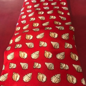 May include: Red silk tie with a repeating pattern of white seashells.