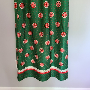 Pu&ograve; includere: Gonna verde con motivo floreale rosso e bianco e pois bianchi. La gonna ha un bordo bianco, rosso e verde in fondo.
