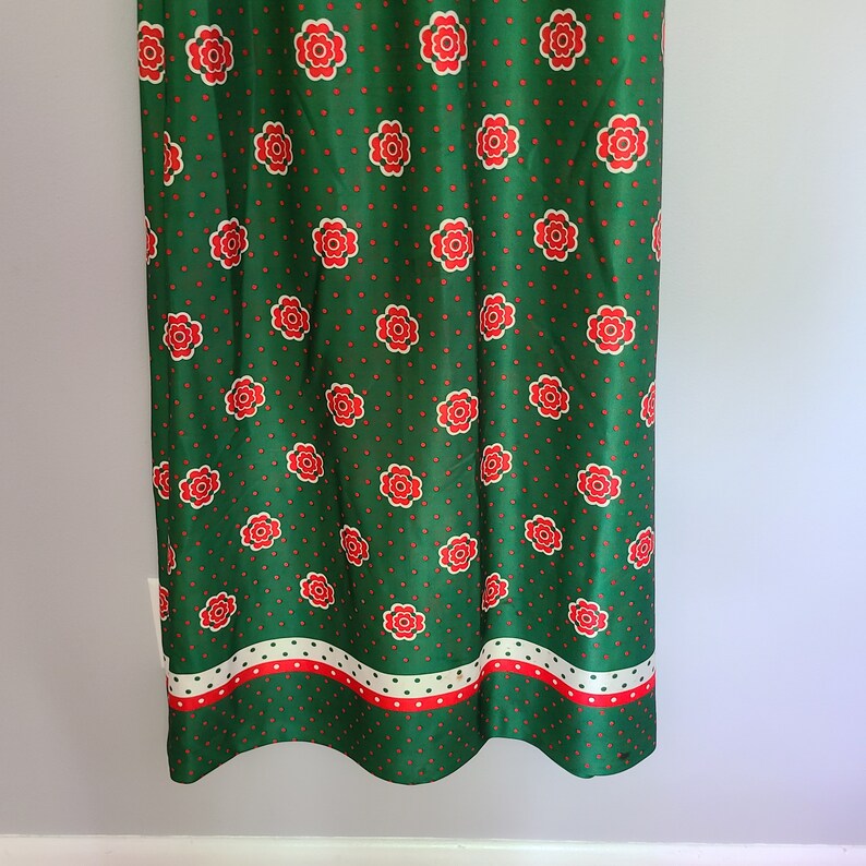 Pu&ograve; includere: Gonna verde con motivo floreale rosso e bianco e pois bianchi. La gonna ha un bordo bianco, rosso e verde in fondo.
