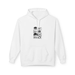 Puede incluir: Sudadera con capucha blanca con bolsillo delantero y gráfico negro. El gráfico presenta las palabras "EAT SLEEP RIDE REPEAT" con iconos de hamburguesa, motocicleta y señal de tráfico.