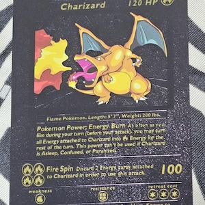 May include: A Charizard Pokémon trading card with a black background. The card features a yellow and orange Charizard illustration with flames. The card text includes "Charizard", "120 HP", and "Fire Spin".