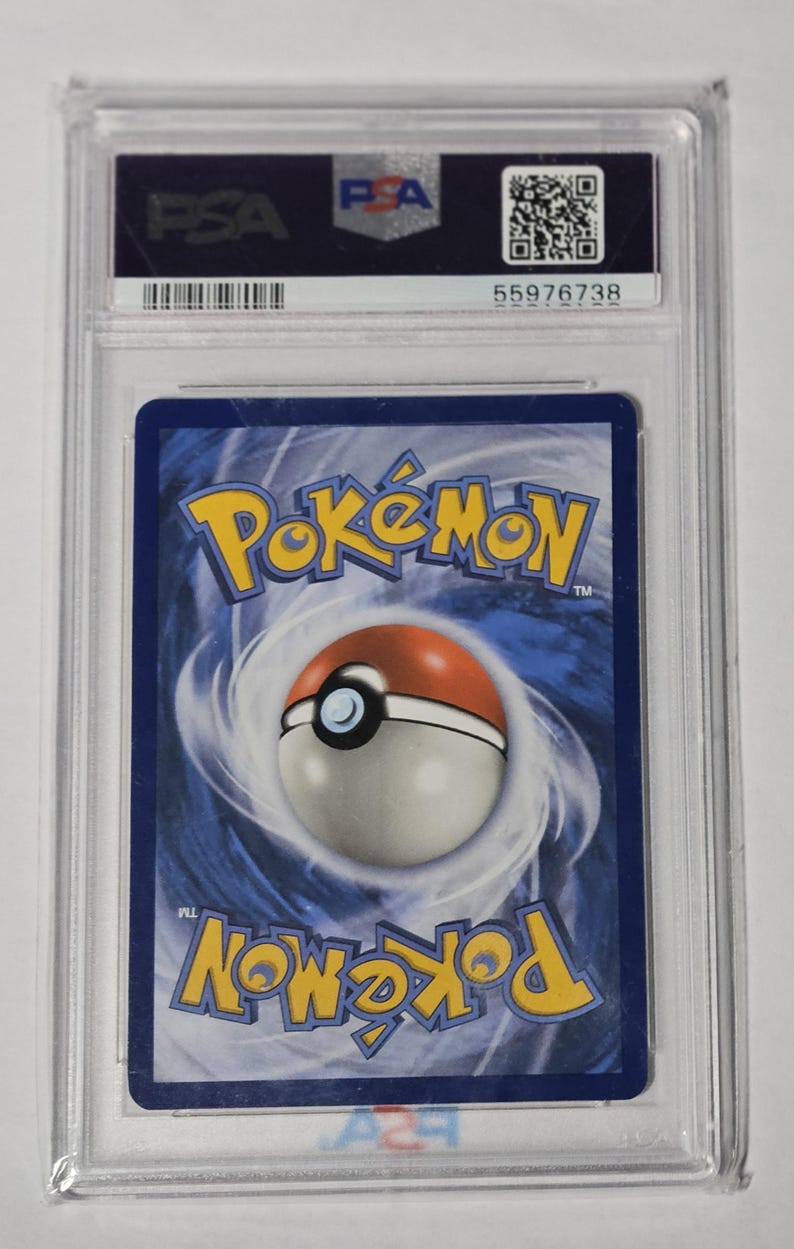 May include: A graded Pok&eacute;mon trading card encased in a clear plastic holder. The card features the Pok&eacute;mon logo and a Pok&eacute; Ball design on a blue background. The holder has a PSA label with a serial number.