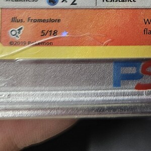 May include: A close-up of a graded trading card encased in a clear plastic holder. The card has a yellow and orange background with text and a logo. The holder has the letters "PSA" in blue and red.