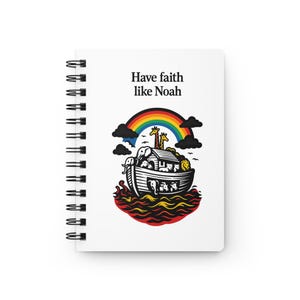 May include: White spiral-bound notebook with the text "Have faith like Noah" above an illustration of Noah's Ark, a rainbow, and animals. The ark is depicted with various animals inside, including giraffes, elephants, and lions.