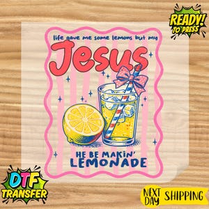 May include: DTF transfer featuring a cartoon illustration of a glass of lemonade with a bow, a lemon, and the text "life gave me some lemons but my Jesus he be makin' lemonade". The design is on a pink background.