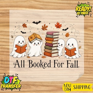 May include: A DTF transfer sheet featuring three white ghosts reading books, a stack of colorful books, orange autumn leaves, and black bats. The text reads All Booked For Fall. The design includes a Ready To Press logo in the top right corner.