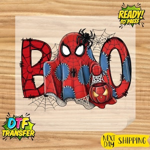 May include: A Halloween-themed DTF transfer featuring a cartoon ghost in a Spider-Man costume. The word "BOO" is spelled out with spiderweb accents. A pumpkin-shaped jack-o'-lantern is also included. The words "READY! TO PRESS" are in the upper right corner.