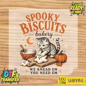 May include: A DTF transfer sheet featuring a gray tabby kitten on a wooden cutting board with a pumpkin, a jack-o'-lantern bowl, and ghost-shaped cookies. Text reads: SPOOKY BISCUITS bakery WE KNEAD EM YOU NEED EM. Includes READY TO PRESS and NEXT DAY SHIPPING labels.