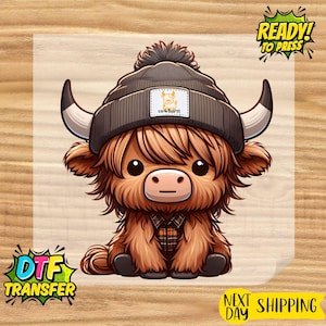 May include: A cartoon illustration of a Highland cow wearing a gray beanie with the text "cowhartt" on the hat. The cow has brown fur, large eyes, and a plaid shirt. The image includes the text "READY! TO PRESS" and "DTF TRANSFER".