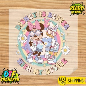 May include: DTF transfer featuring Minnie Mouse and Daisy Duck with sunglasses, standing together in front of a rainbow background. The text reads "Disney is Better With My Bestie". Includes "Ready to Press" and "Next Day Shipping" text.