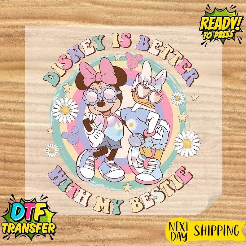 May include: DTF transfer featuring Minnie Mouse and Daisy Duck with sunglasses, standing together in front of a rainbow background. The text reads "Disney is Better With My Bestie". Includes "Ready to Press" and "Next Day Shipping" text.