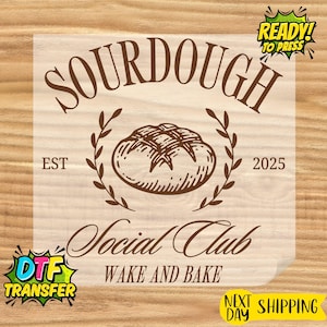 May include: A brown DTF transfer with the words "SOURDOUGH Social Club" and "WAKE AND BAKE". The design includes a bread loaf illustration, the year 2025, and the text "READY! TO PRESS".