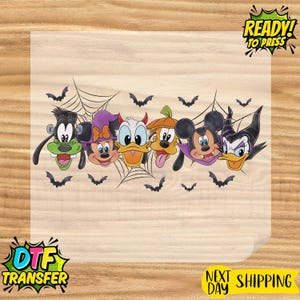 May include: A DTF transfer sheet featuring a colorful graphic of six cartoon characters dressed in Halloween costumes, including a Frankenstein-style character, a witch, a devil, a pumpkin, a vampire, and a horned villain, surrounded by spiderwebs and bats.