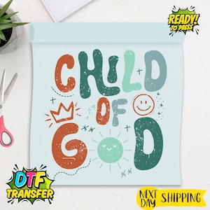 May include: A light blue DTF transfer sheet with the words "CHILD OF GOD" in various colors and fonts. The design includes a crown, a smiling sun, and other decorative elements. The words "READY TO PRESS" and "DTF TRANSFER" are also visible.