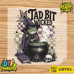 May include: A DTF transfer sheet featuring a green frog wearing a purple witch hat and cape, stirring a black cauldron with white smoke rising. The text reads Tad Bit Wicked. Includes a book titled Spells & Brews, a skull, and potion bottles.
