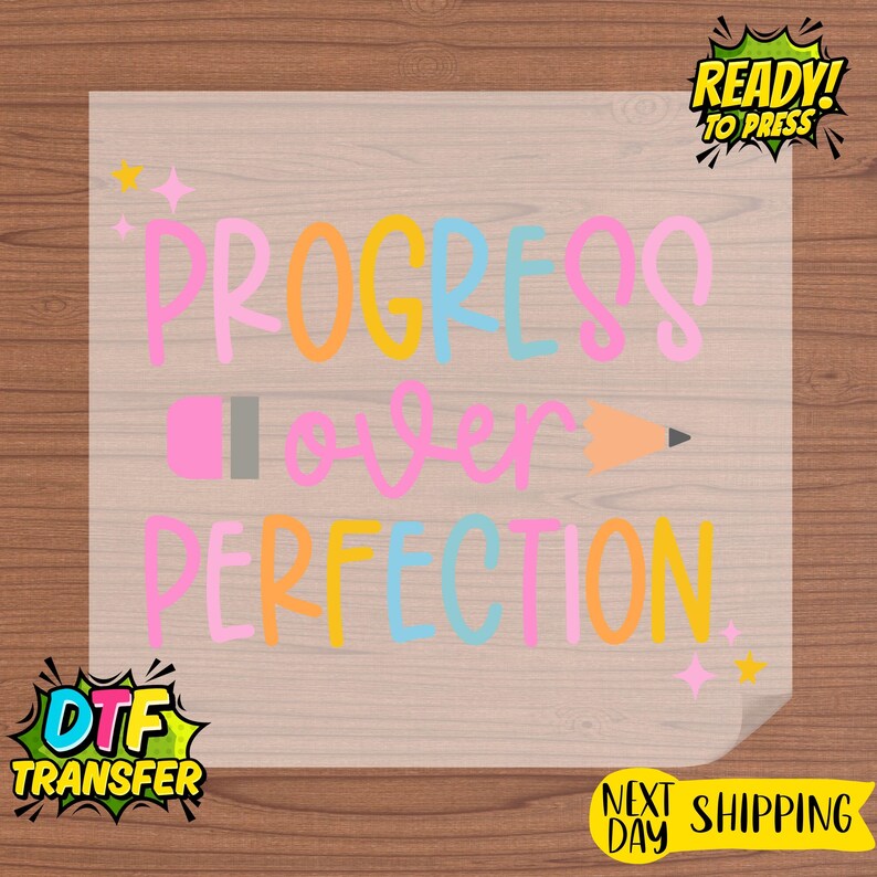 May include: A transparent DTF transfer with the text "PROGRESS OVER PERFECTION" in pink, orange, yellow, and blue. A pink pencil and orange pencil are also featured. The transfer is ready to press.