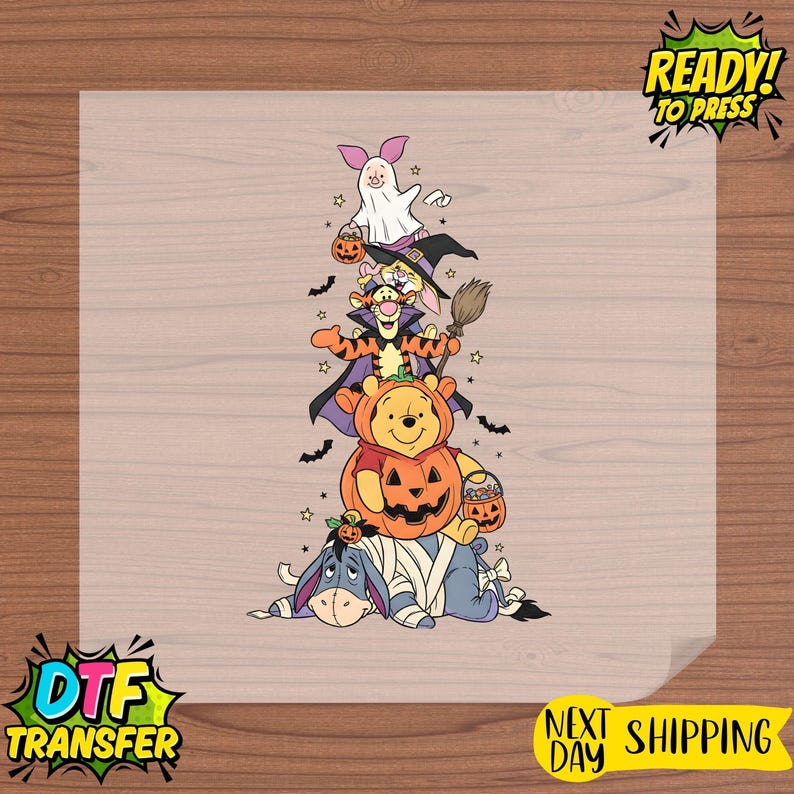Op de afbeelding: Een warmteoverdrachtssticker met een verticale stapel stripfiguren verkleed voor Halloween. Knorretje is een spook, Konijn draagt een heksenhoed, Teigetje een cape, Winnie de Poeh zit in een pompoen en Iejoor is als een mummie ingewikkeld.