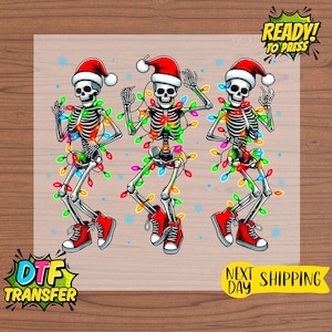 May include: DTF transfer featuring three dancing skeletons wearing Santa hats, red sneakers, and colorful Christmas lights. The skeletons have a festive holiday theme, with the words "READY! TO PRESS" and "NEXT DAY SHIPPING" in the image.