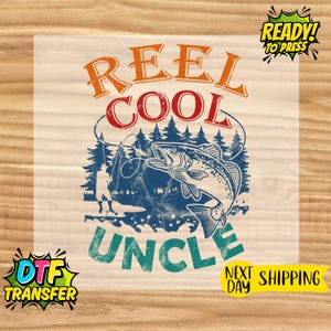 May include: A DTF transfer with a fishing theme. The design features the words "REEL COOL UNCLE" in orange, red, and teal, with a blue illustration of a fish, trees, and a fisherman. The words "READY! TO PRESS" are also included.