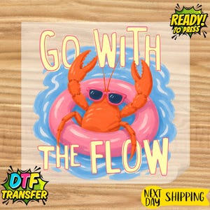 May include: A DTF transfer sheet featuring a bright orange lobster wearing dark sunglasses, floating in a pink inner tube on blue water. The text GO WITH THE FLOW is printed in large yellow letters above and below the lobster illustration.