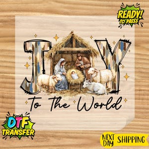 May include: DTF transfer featuring a nativity scene with the text "Joy to the World." The image depicts Mary, Joseph, and baby Jesus in a manger, surrounded by sheep and a goat. The word "Joy" is stylized with a textured design.