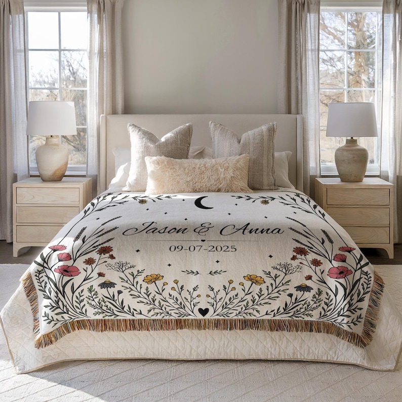 May include: A cream-colored throw blanket with a floral design and the names "Jason & Anna" and the date "09-07-2025" printed on it. The blanket has a fringe border and is decorated with flowers in red, yellow, and black.