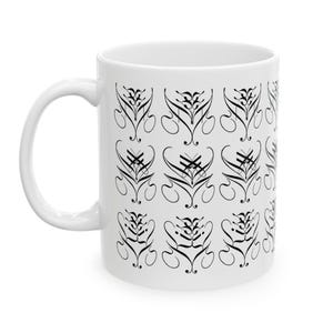 May include: A white ceramic mug featuring a repeating black calligraphic pattern. The design consists of stylized, symmetrical flourishes arranged in a grid, with the text "Kiss My" visible in a decorative script font along the right side.