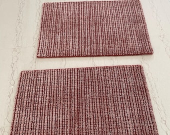 Puede incluir: Tres alfombras rectangulares dispuestas en una fila vertical. Cada alfombra presenta un color rojo intenso con una superficie texturizada y acanalada que consiste en líneas verticales alternas de material con mechones y secciones tejidas.