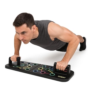 Può includere: Una tavola per flessioni nera con segni colorati e maniglie. Una persona sta facendo flessioni usando la tavola. La parola "CHEST" è stampata sulla tavola. La tavola è progettata per varie posizioni di flessioni.