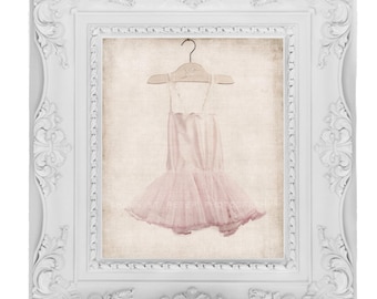 May include: A white ornate frame with a pink tulle tutu hanging on a wooden hanger. The tutu is on a beige background with a subtle texture.