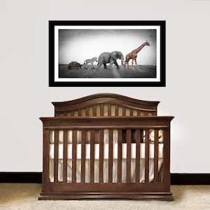May include: A black and white photograph of a turtle, zebra, elephant, and giraffe walking in a line. The photograph is framed and hanging above a brown wooden cot.