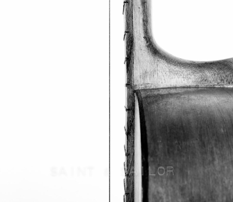May include: Close-up of the side of an acoustic guitar, showing the wood grain and the strings. The guitar is black and has a natural wood finish.