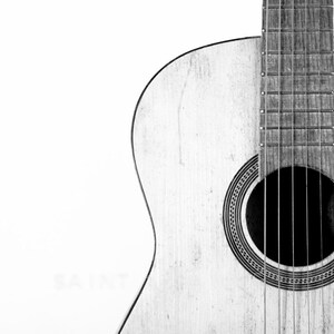 May include: A close-up of a wooden acoustic guitar with a sound hole and strings. The guitar is in black and white.