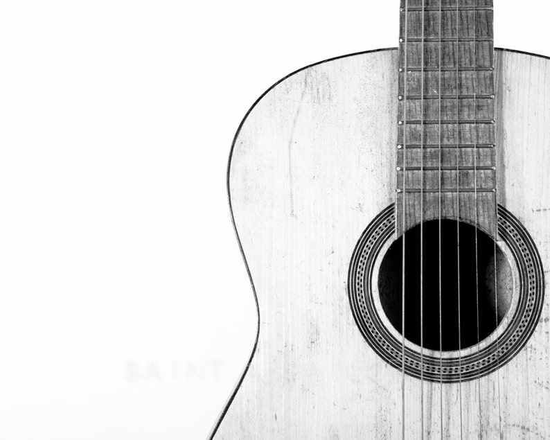 May include: A close-up of a wooden acoustic guitar with a sound hole and strings. The guitar is in black and white.