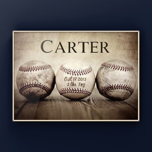May include: A framed print featuring three baseballs with the name "CARTER" above them. The center baseball has the date "Oct 17 2013" and the weight "2 lbs 7oz" printed on it. The background has a vintage, aged appearance.