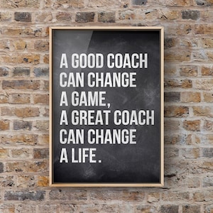 May include: A black chalkboard with a white wooden frame hangs on a brick wall. The chalkboard has the text "A GOOD COACH CAN CHANGE A GAME, A GREAT COACH CAN CHANGE A LIFE." written on it.