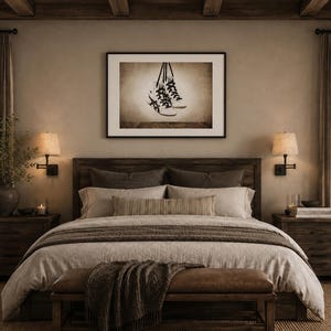 May include: A framed wall art print featuring a sepia-toned illustration of a pair of high-top sneakers with black laces hanging by their laces. The artwork is displayed in a simple black frame and is centered above a wooden bed frame in a bedroom.