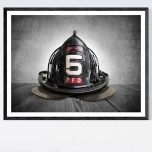 May include: A black firefighter helmet with a white number "5" and the letters "PFD" on the front. The helmet is sitting on a wooden surface.
