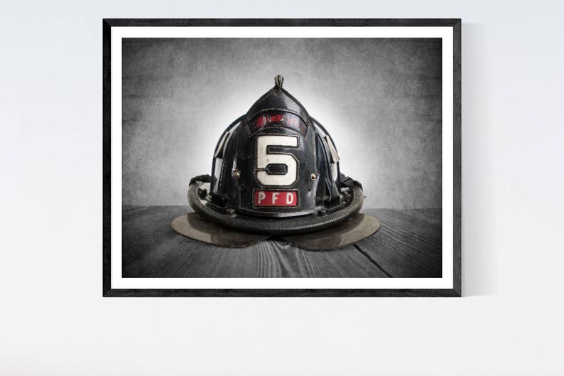 May include: A black firefighter helmet with a white number "5" and the letters "PFD" on the front. The helmet is sitting on a wooden surface.