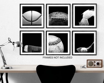 May include: Black and white framed prints featuring close-up images of sports equipment. The set includes a basketball, football, soccer ball, baseball, and golf club. The text "FRAMES NOT INCLUDED" is visible below the prints.