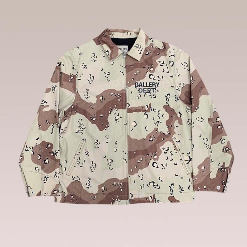 Puede incluir: Chaqueta de camuflaje en tonos beige, marr&oacute;n y negro, con el texto azul marino "GALLERY DEPT" en el pecho. La chaqueta tiene cuello, cremallera y dos bolsillos delanteros. La chaqueta es de color neutro y apta para cualquiera.