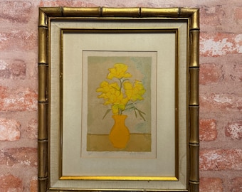 May include: A framed print featuring a yellow vase filled with yellow flowers. The artwork is encased in a gold-colored frame with a textured bamboo-style design and a light-colored matting, presenting a centered floral composition on a neutral background.