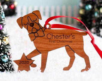 May include: A wooden Christmas ornament shaped like a boxer dog holding a star with the text "2020" on it. The ornament is personalized with the text "Chester's First Christmas".