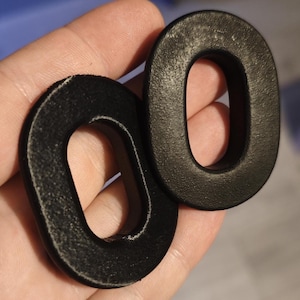 Peut inclure: Deux coussinets d'oreille noirs de forme ovale. Les coussinets ont une surface texturée et un intérieur doux et rembourré. Les coussinets sont conçus pour s'adapter sur les oreilles et offrir confort et isolation phonique.