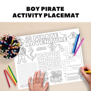May include: A white activity placemat with the text "BOY PIRATE ACTIVITY PLACEMAT" and "PIRATE ADVENTURE". The placemat features pirate-themed illustrations, a maze, a crossword puzzle, and a word search. Colored pencils and crayons are visible.