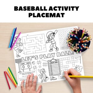 May include: A white baseball activity placemat with black line drawings of baseball players, a maze, and a crossword puzzle. The text "BASEBALL ACTIVITY PLACEMAT" and "LET'S PLAY BALL!" are at the top and center. Colored pencils and crayons are nearby.