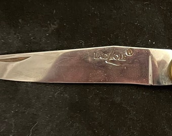 May include: A silver pocket knife with a wooden handle and a corkscrew. The knife has a brass accent and the words "Laguiole" engraved on the blade.