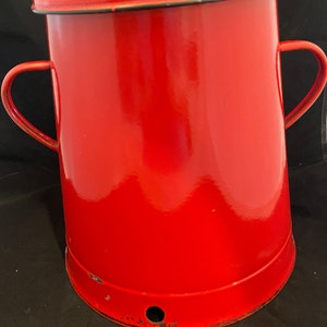May include: A red enamelware pot with a lid and two handles. The pot has a small hole in the bottom.